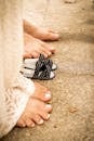 Close-up of a pregnant woman's bare feet next to sandals on a sunlit pavement.