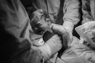 Black and white photograph capturing a newborn baby being delivered in a hospital by medical staff.